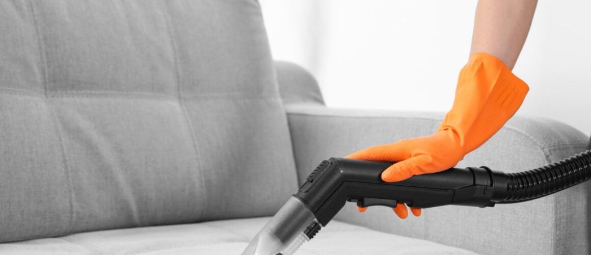 Woman with vacuum cleaner cleaning couch